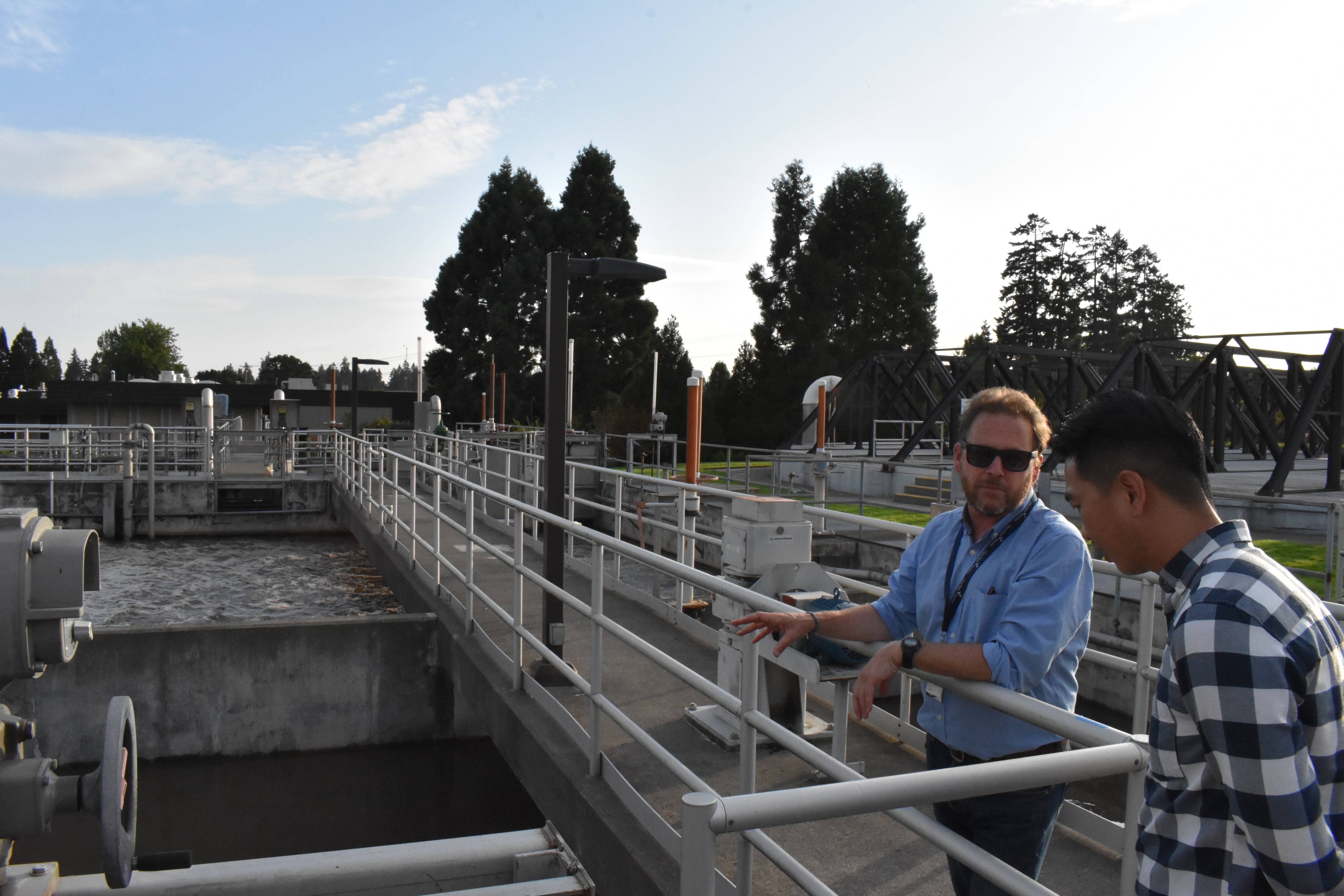 Two men talk at a wastewater treatment plant