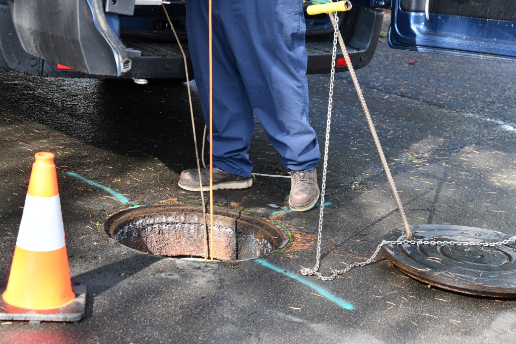 An image of a person standing in front of a manhole